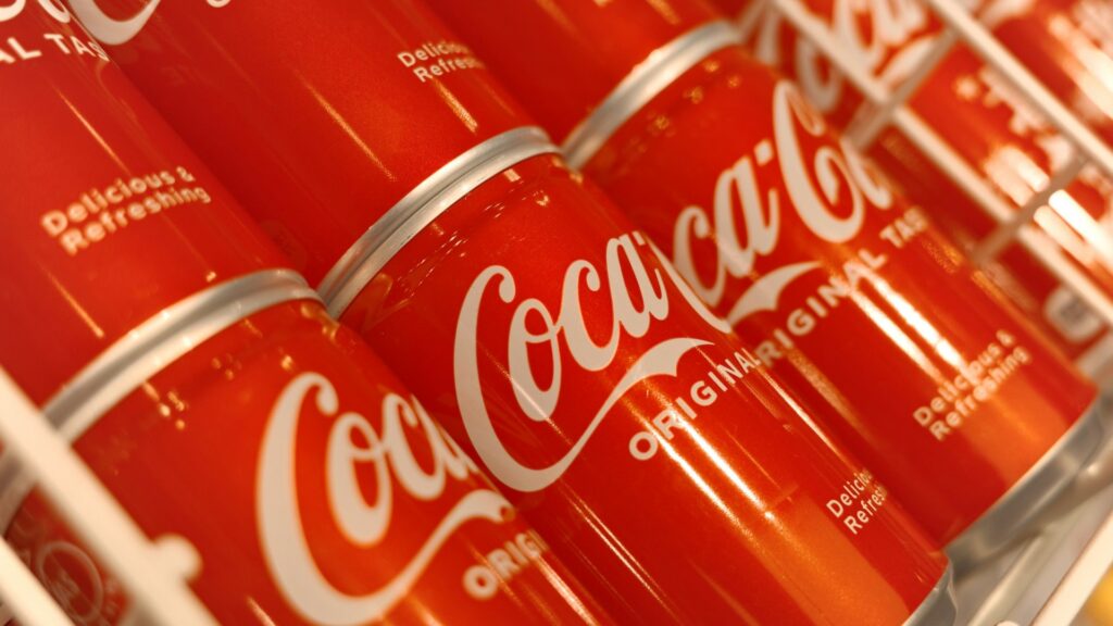 Blikjes Coca-Cola Original Taste in een winkelrek, passend bij een Coca-Cola groothandel assortiment